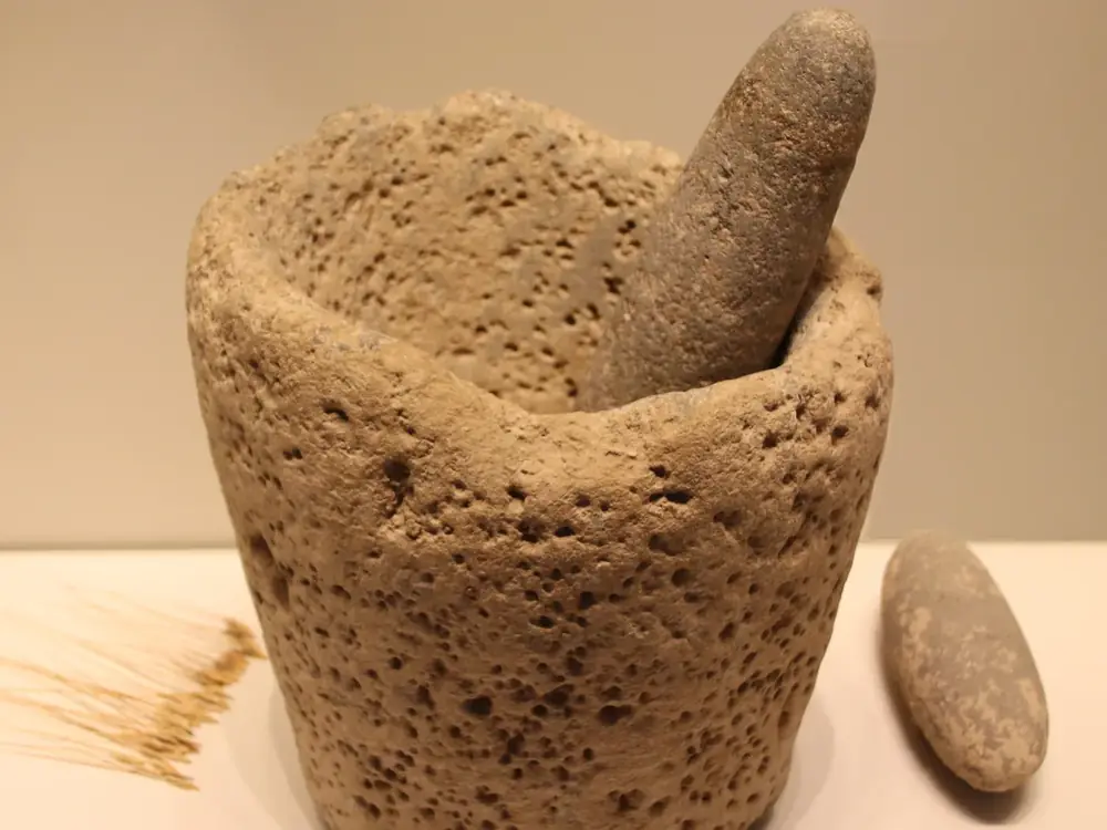 A deep stone mortar with a stone pestle resting in it