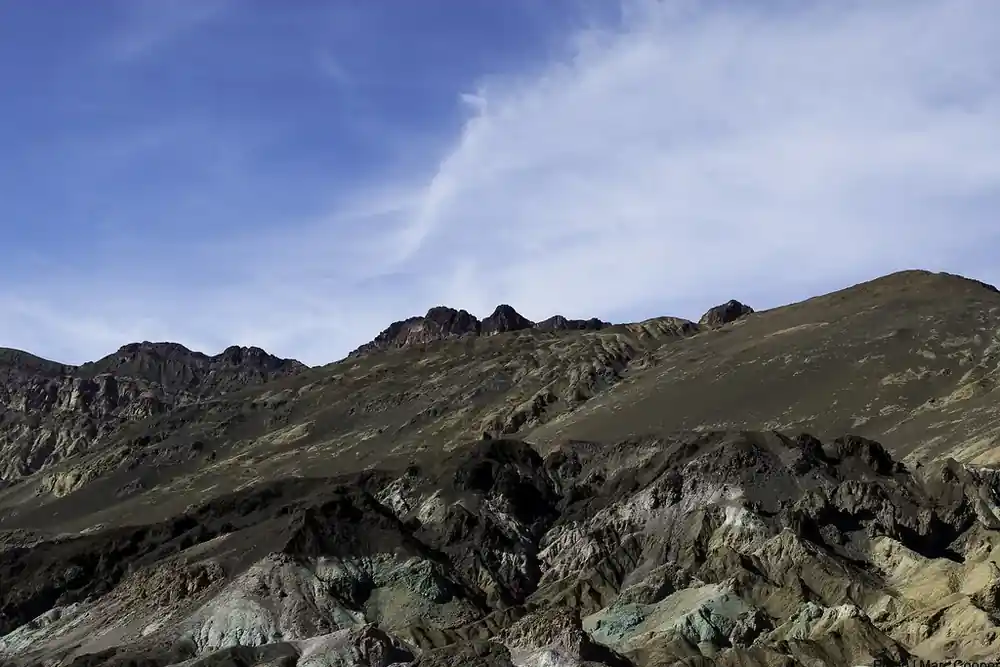 A hillside of bare, weathered mineral under a pale sky