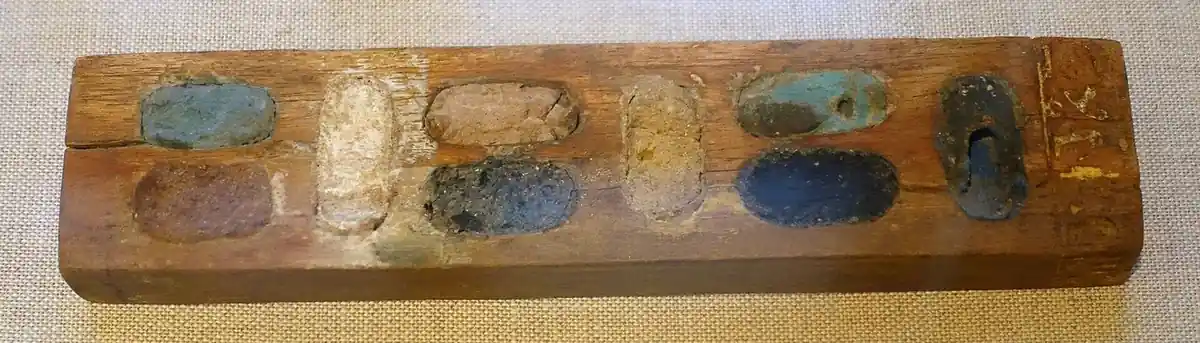 A wooden paint box holding cakes of mineral colour in shallow wells
